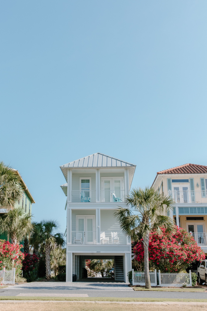A beautiful tropical house surrounded by palm trees and vibrant flowers.